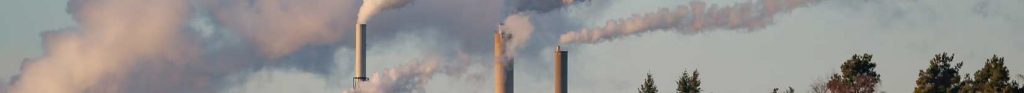 Smoke rising towards the sky from the chimneys of a paper mill
